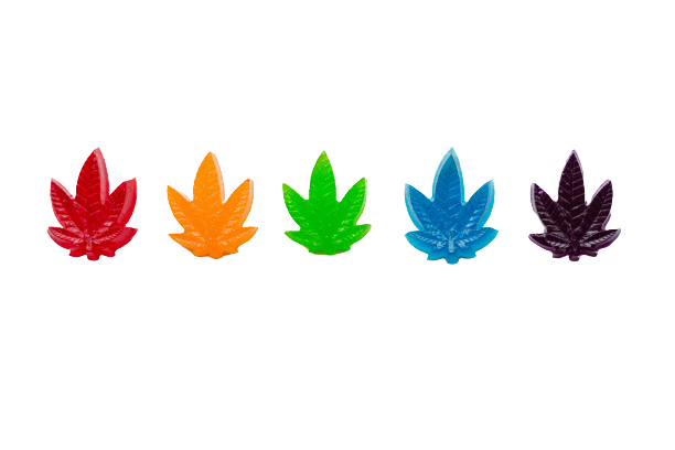 Candy gummies shaped as cannabis leaves over white background