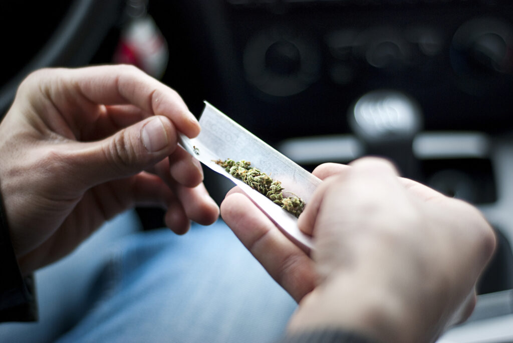 Hombre liando un porro de marihuana en el coche