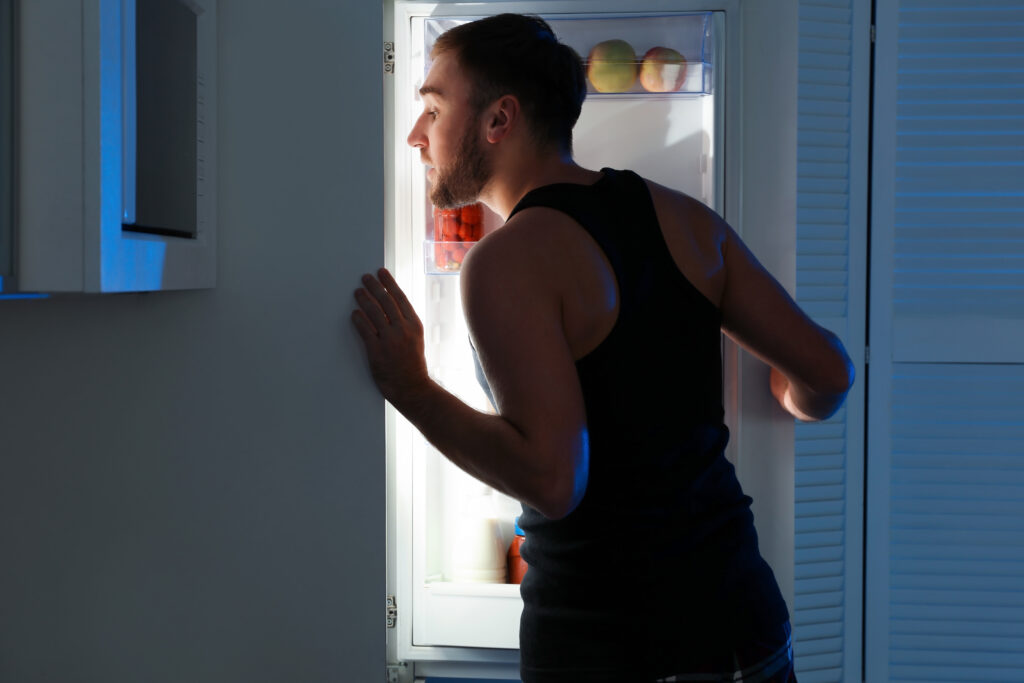 Man taking products out of refrigerator in kitchen at night